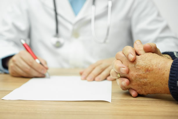 Physician taking notes while sitting with patient